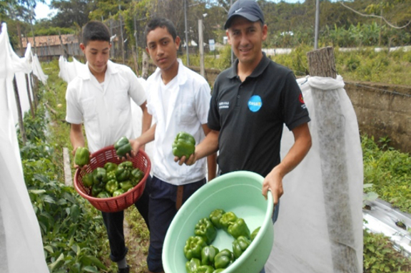 Beneficiaros mostrando producto del huerto