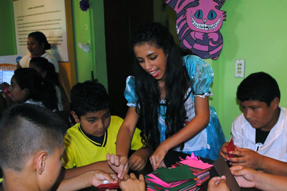 Personaje de Alicia en el pa�s de las maravillas junto a ni�os en una mesa