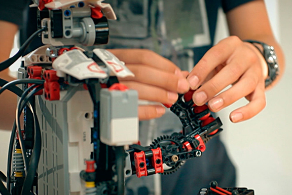 Las manos de un joven armando las piezas de un robot con legos