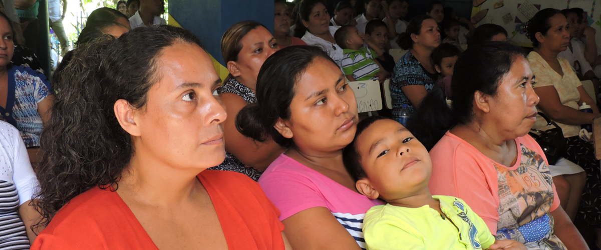 Fotograf�a de un grupo de personas en una reuni�n, en primer plano una mujer con un ni�o en brazos