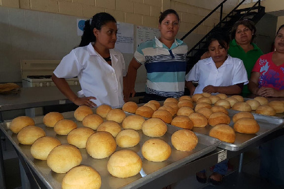 Foto j�venes mostrando producto taller de panader�a