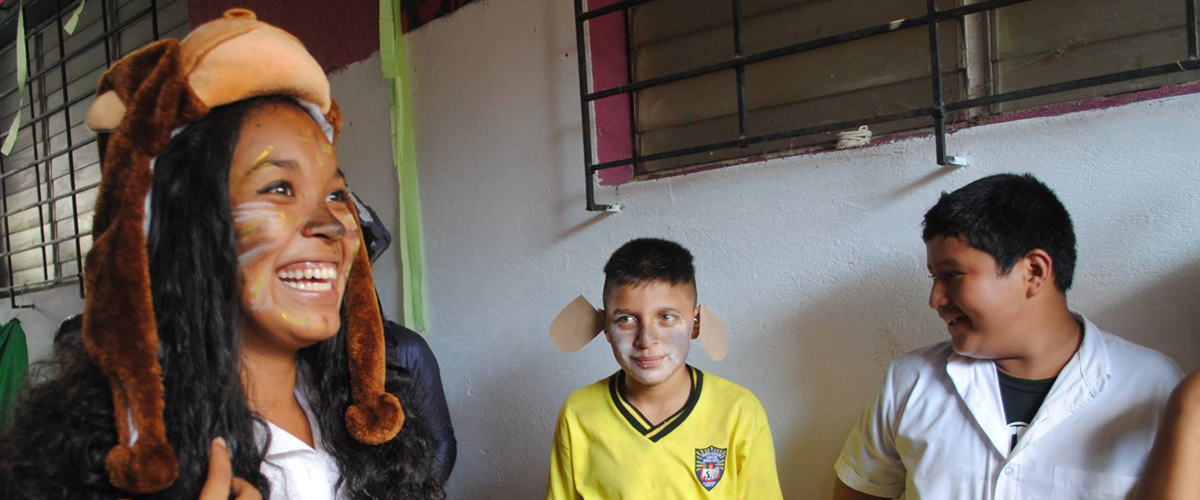 Ni�a con el rostro pintado con bigotes y sobre su cabeza la figura de un mono en un gorro