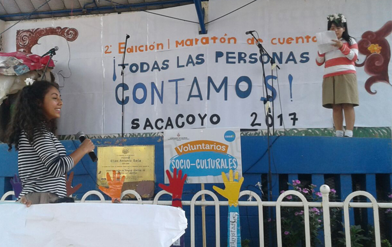 2 ni�as representando un cuento, tras ellas el t�tulo de II Edici�n Marat�n de Cuentacuentos `Todas las personas contamos` 2017